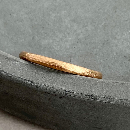 Two handcrafted wedding rings with subtle textures placed on top of a stack of books, with the title 'SILENCE' visible in the background.