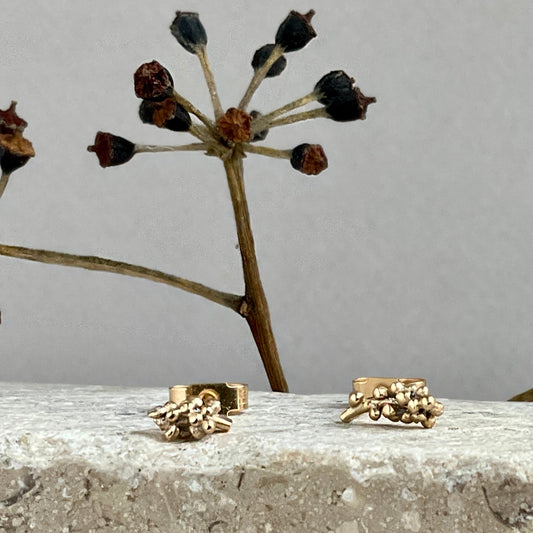 Gold ring with floral design on a stone surface with a gray background