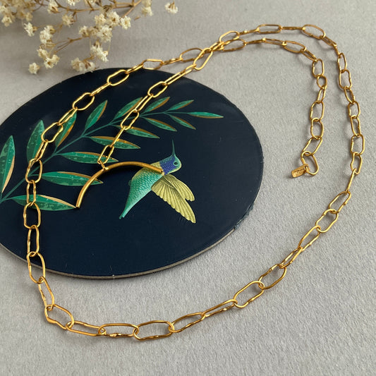 Gold chain necklace on a decorative background with a bird and leaf design.