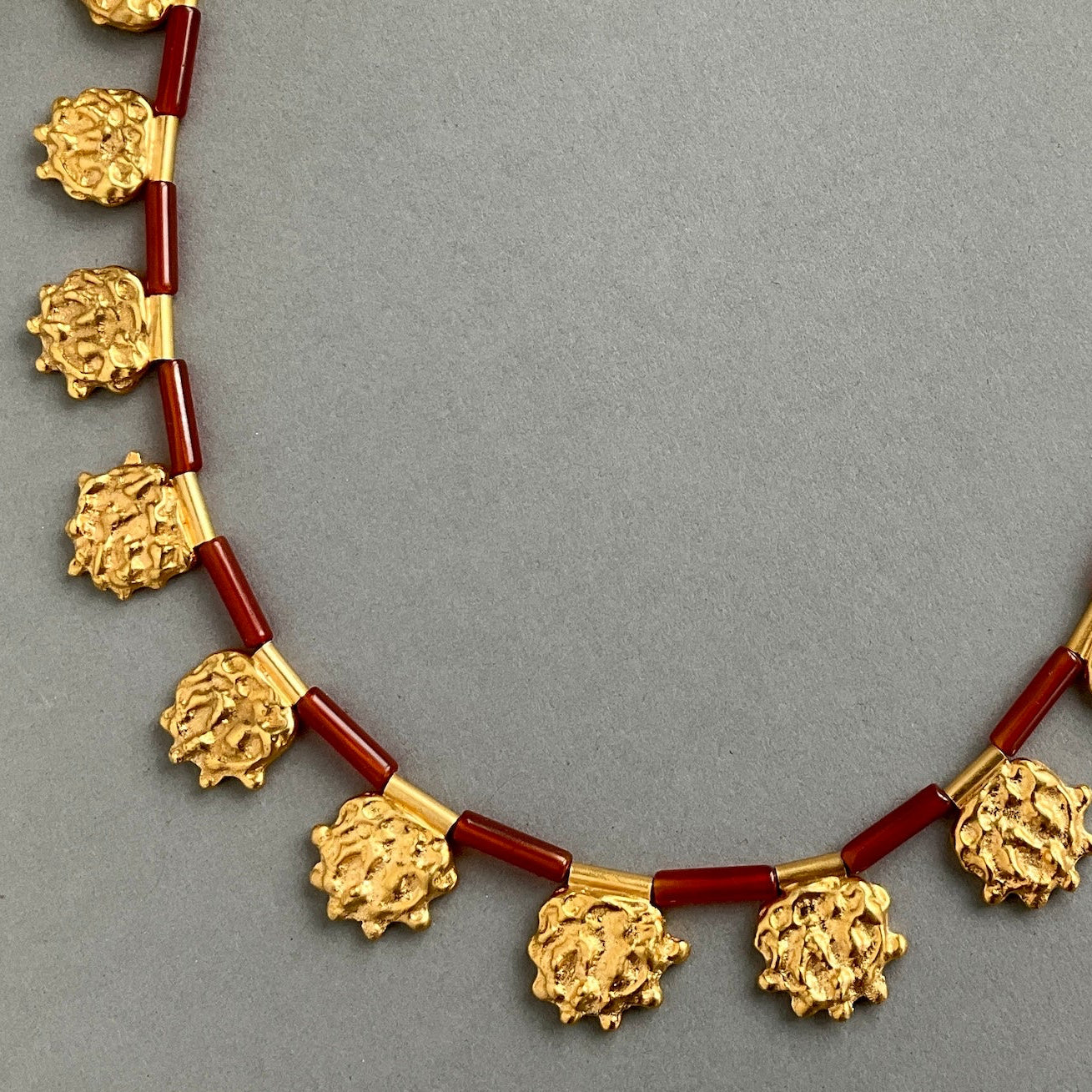 Necklace with gold and red beads on a gray background