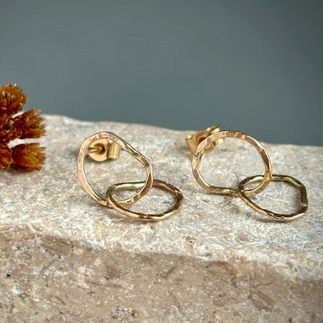 Gold hoop earrings on a textured surface with a neutral background