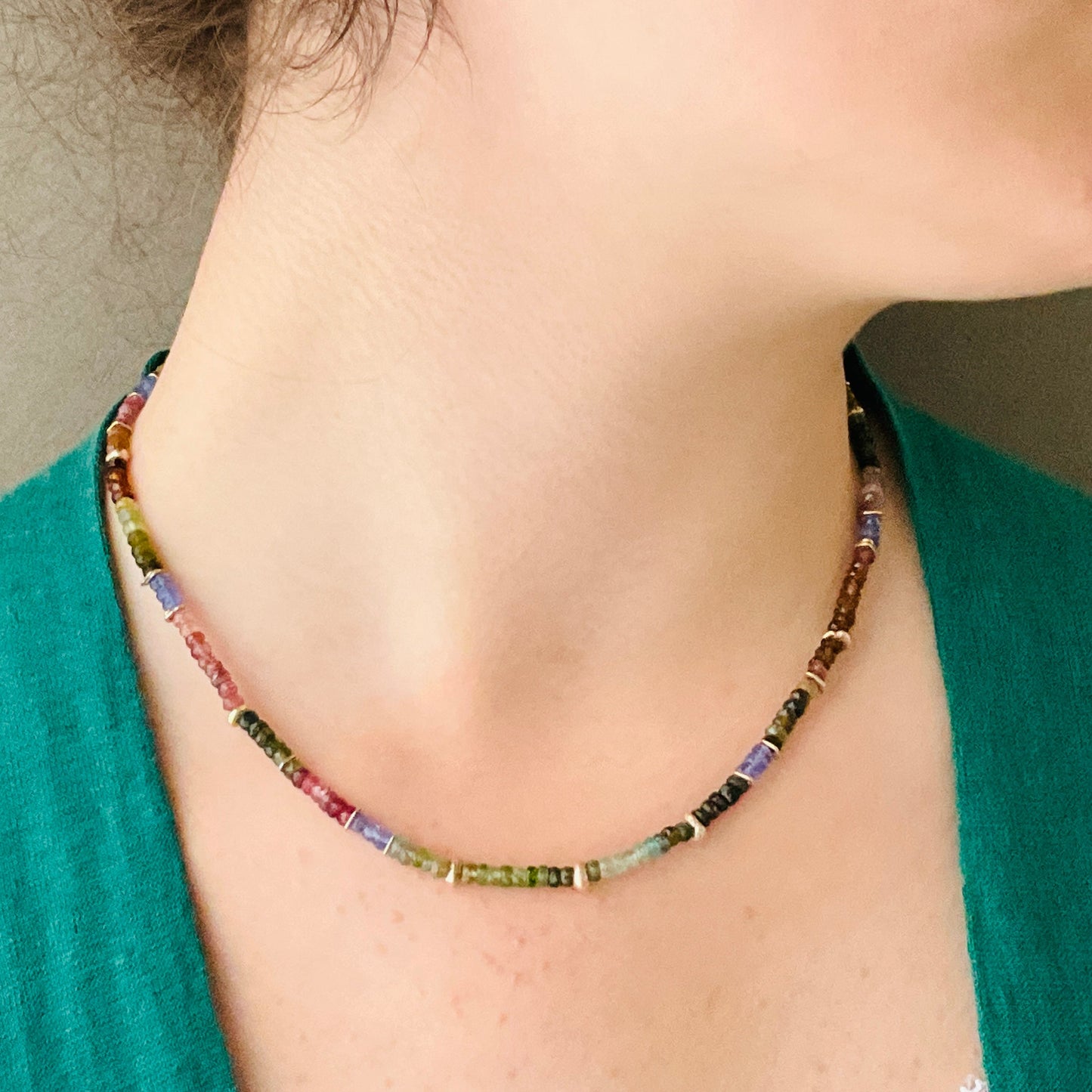 Multicolored beaded necklace worn by a person with a green top.