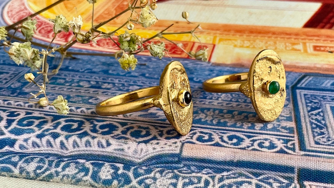 Two gold rings laying in a book with gemstones
