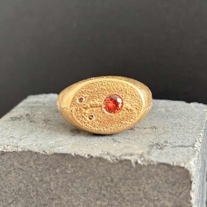 Gold ring with a red gemstone on a gray surface with a black background