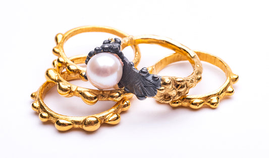 group of five rings recycled 24ct yellow gold vermeil with bubbles and textures one with a round white pearl in a white background
