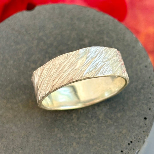 Silver ring on a textured stone surface with red leaves in the background