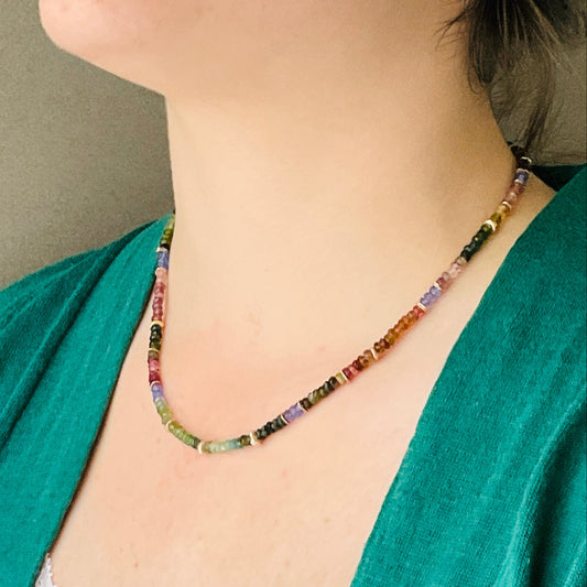Multicolored beaded necklace worn by a person with a green top.
