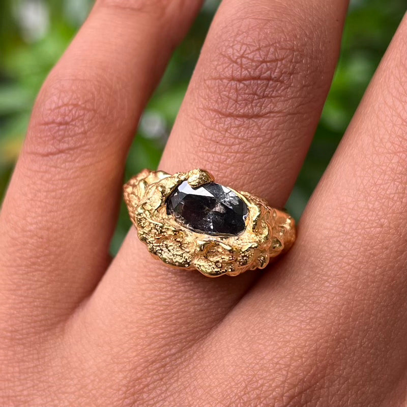 plethora gold ring with a smokey black coloured cubic zirconia gemstone modelled in a hand