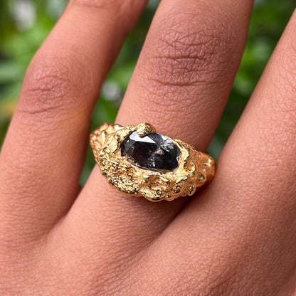 plethora gold ring with a smokey black coloured cubic zirconia gemstone modelled in a hand