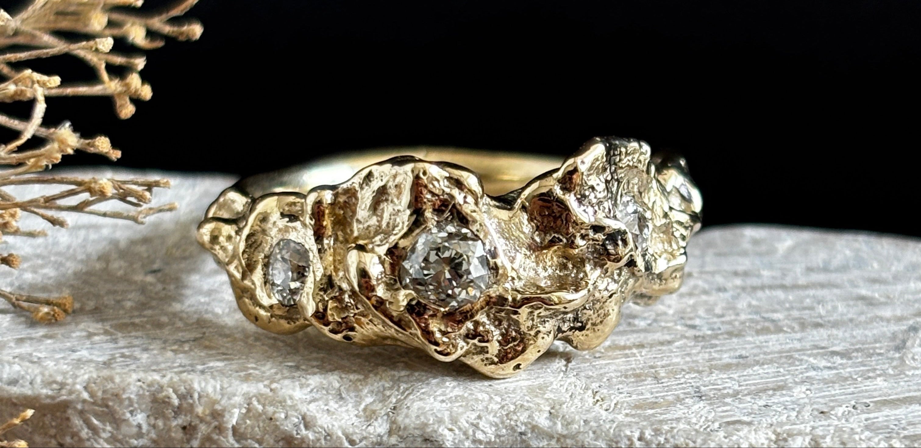 Gold ring with diamond accents on a textured surface with a dark background