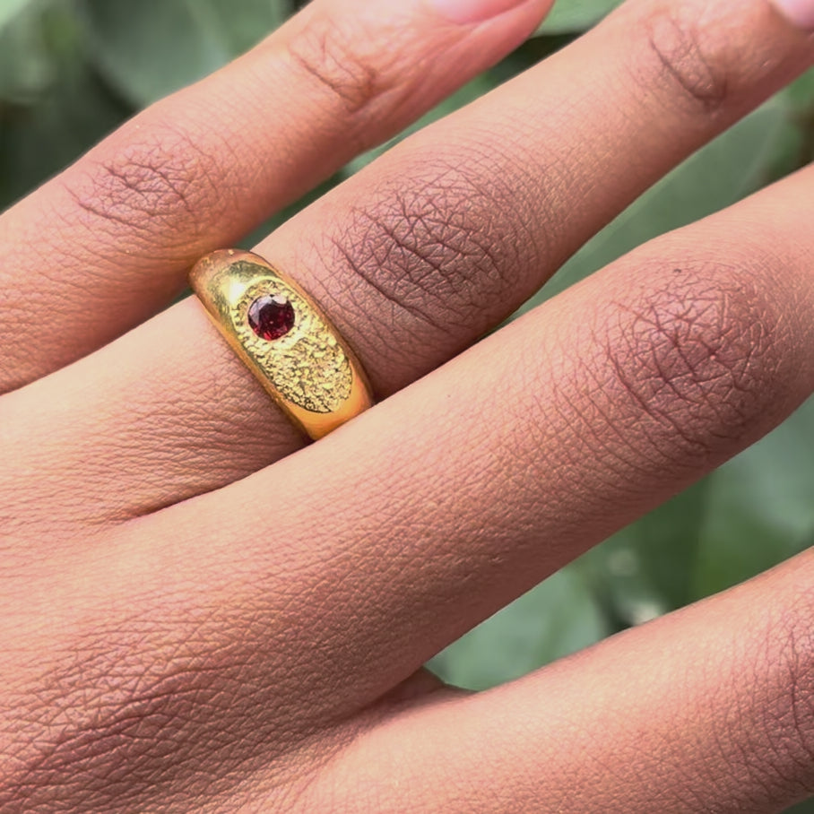gold signet ring with a Mozambique garnet gemstone modelled in a finger