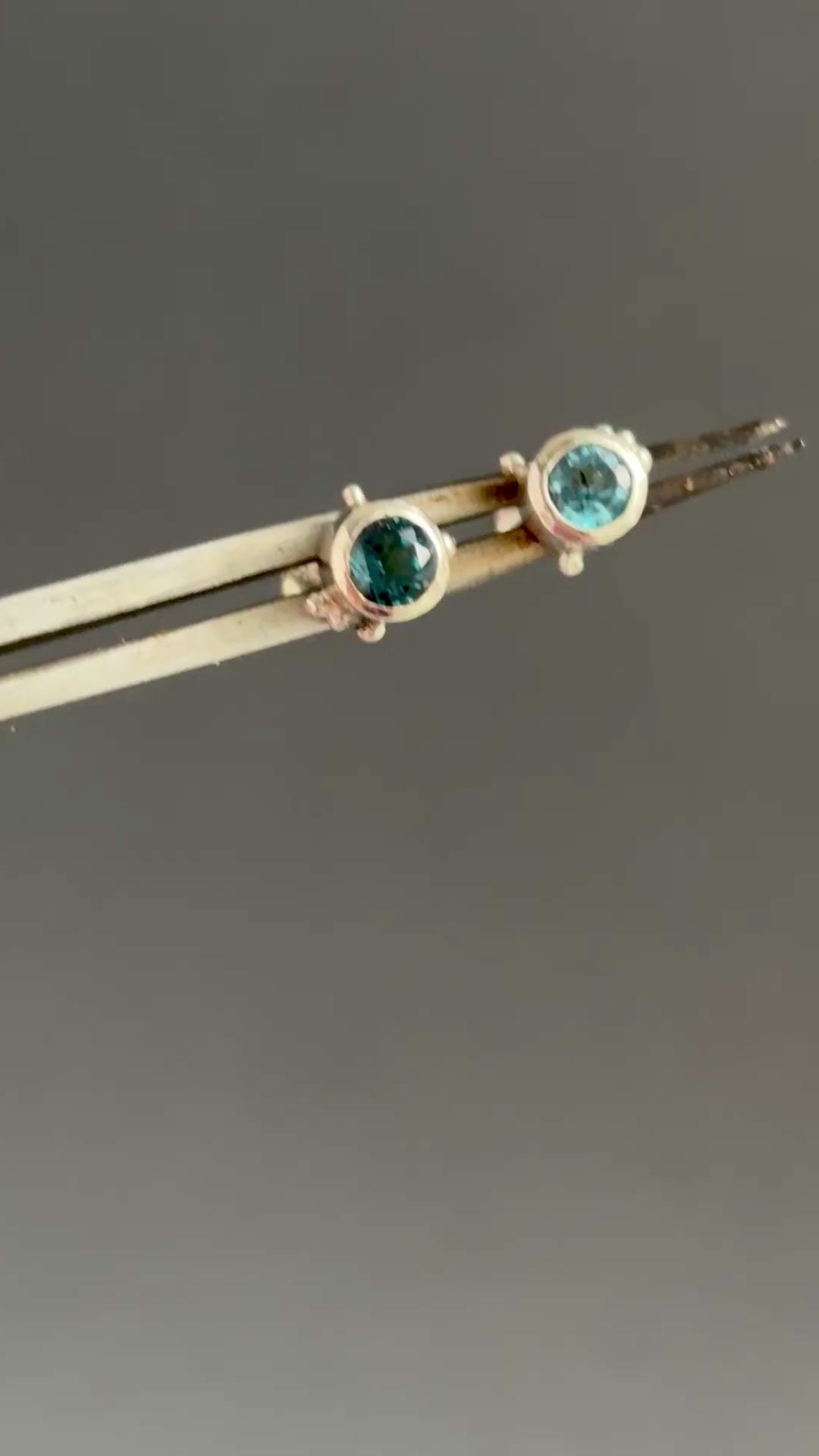 In this video the plethora stud earrings, very simple 4mm round faceted London blue topaz gemstones with some granules details. Grey background 